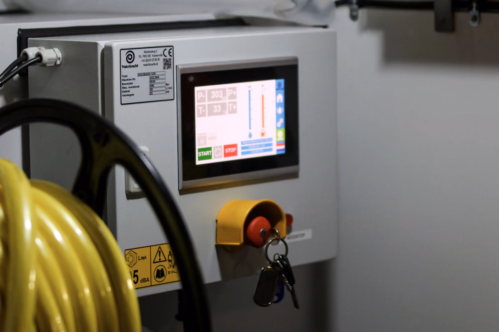 Panel de control industrial con pantalla de controlador programable y parada de emergencia.