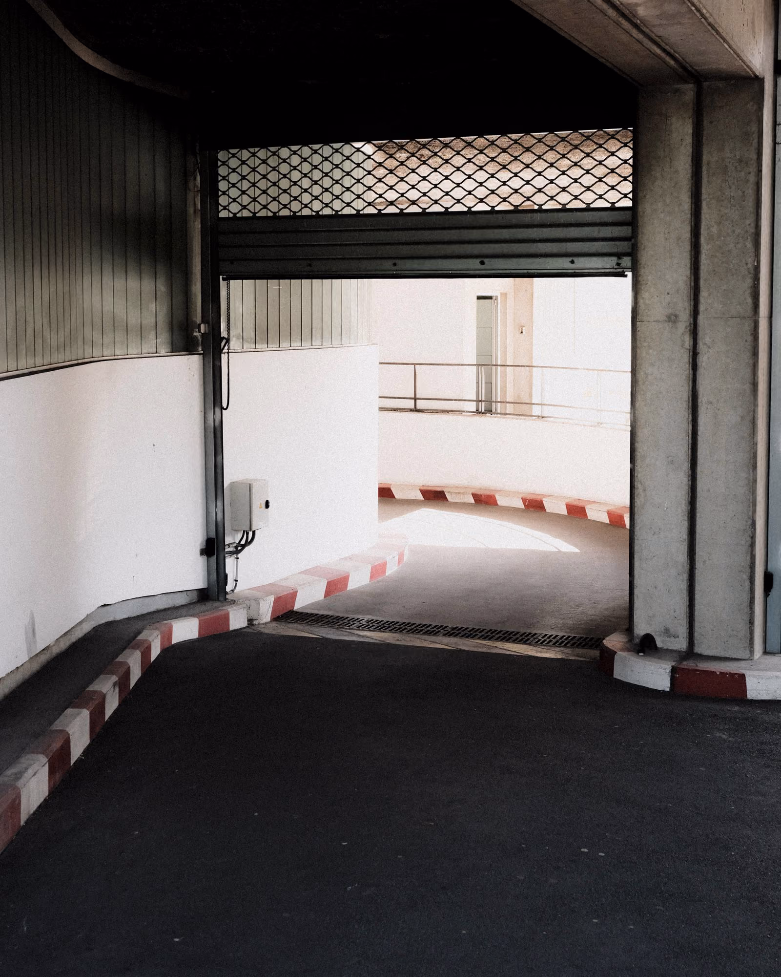 Rampa de acceso vehicular a un estacionamiento interior con barrera.